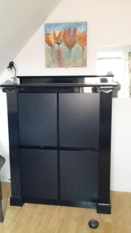 un comò nero in una stanza con un dipinto sul muro di didi logement a Westerlo