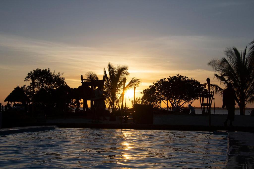 a sunset over a swimming pool at a resort at Fruit & Spice Wellness Resort Zanzibar in Kizimkazi