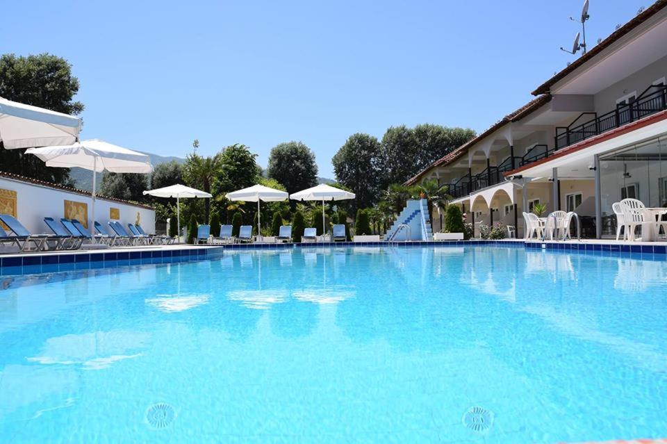 uma grande piscina azul com cadeiras e guarda-sóis em Hotel Afroditi em Paralia Panteleimonos