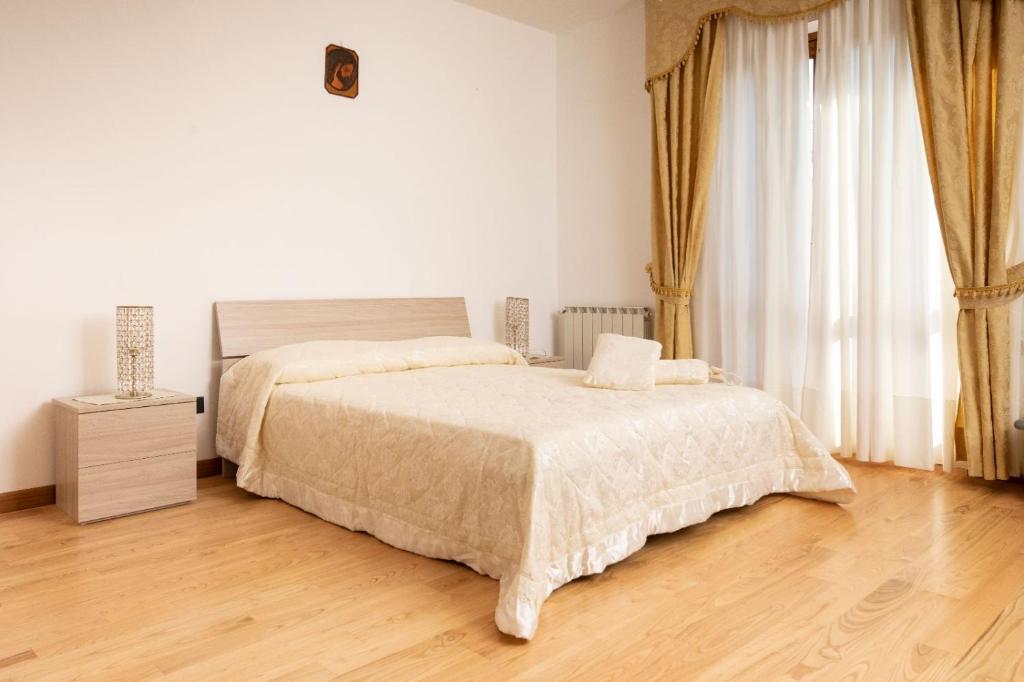 a white bedroom with a bed and a wooden floor at B&B Antares in Cittanova