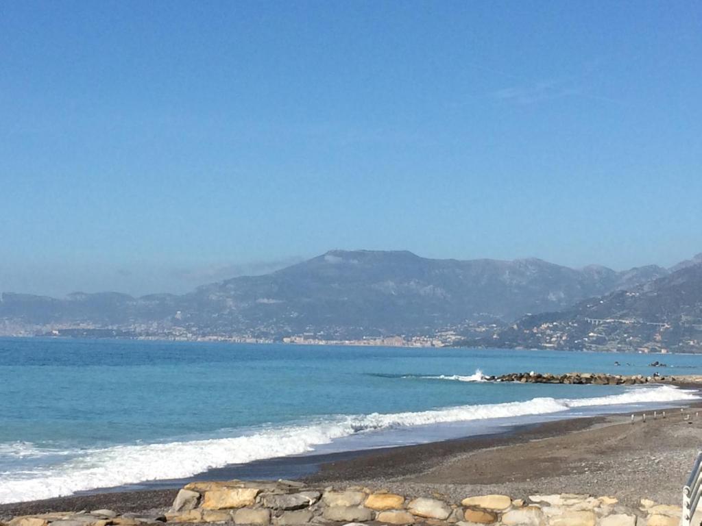 a beach with blue water and mountains in the background at Ocean in Bordighera