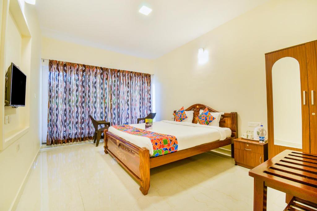 een slaapkamer met een bed, een tv en een raam bij FabHotel Vinu Valley Resorts in Ooty