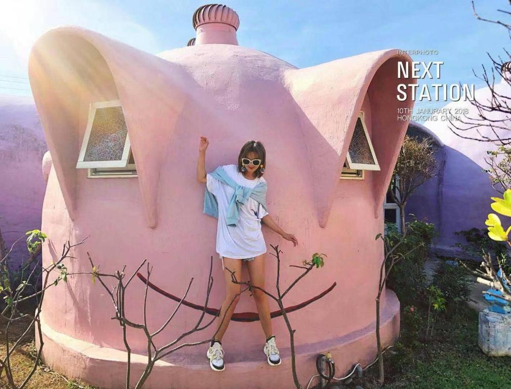 a woman standing in front of a pink house at Kenting Ha-Bi Star Fort in Hengchun