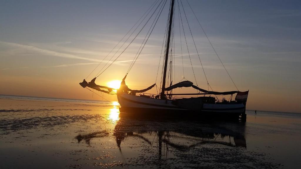 a boat sitting on the beach at sunset at tjalkjacht pelikaan enkhuizen in Enkhuizen