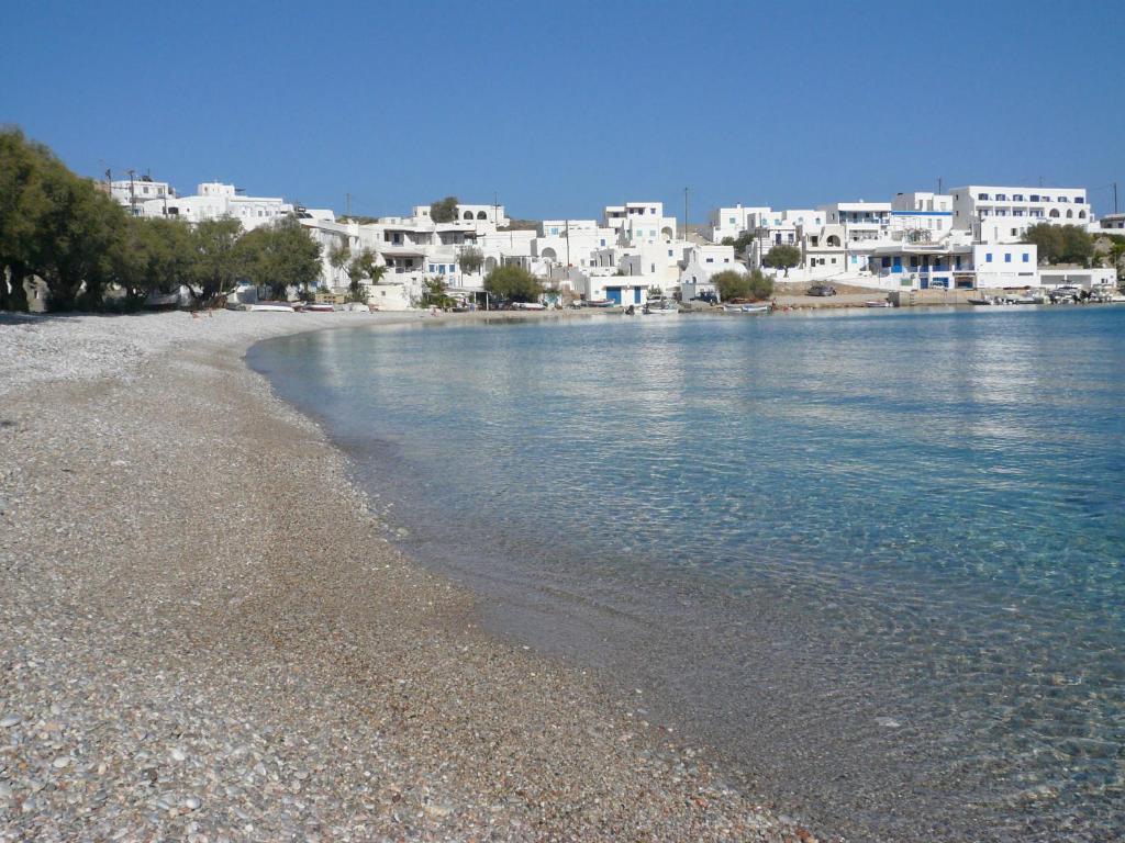 a beach with white buildings and the water at Vrahos Boutique Hotel in Karavostasi