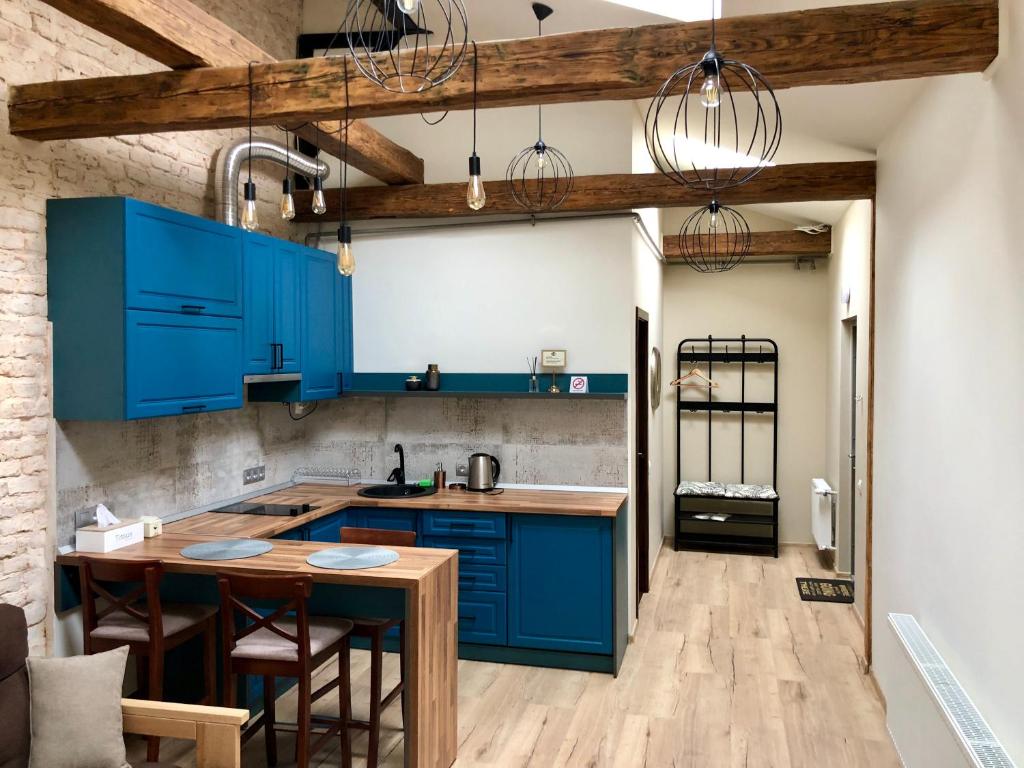 eine Küche mit blauen Schränken und einem Holztisch in der Unterkunft Apartment in Lwiw