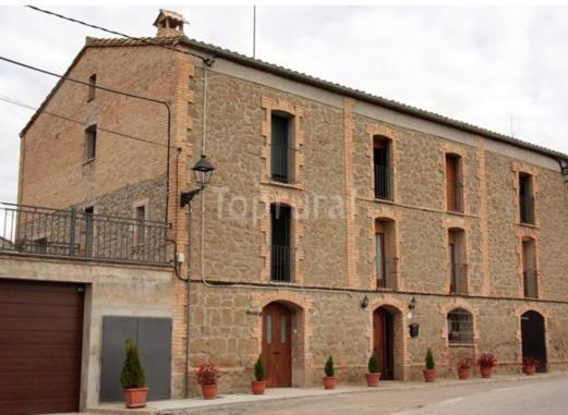 un gran edificio de ladrillo con plantas delante en Casa Cal Fuster, en Sant Climéns