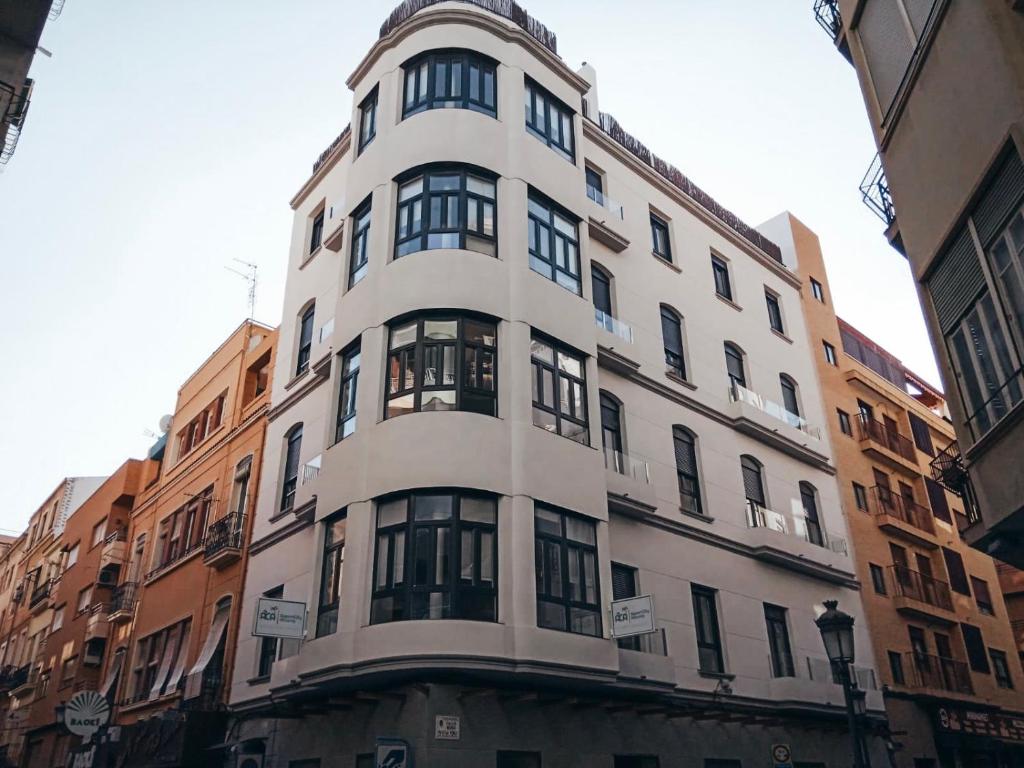 een hoog wit gebouw met ramen aan een straat bij Alicante Center Apart in Alicante