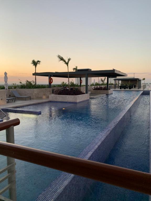 einen Pool in einem Resort mit Sonnenuntergang im Hintergrund in der Unterkunft La Amada condo with Marina View in Cancún