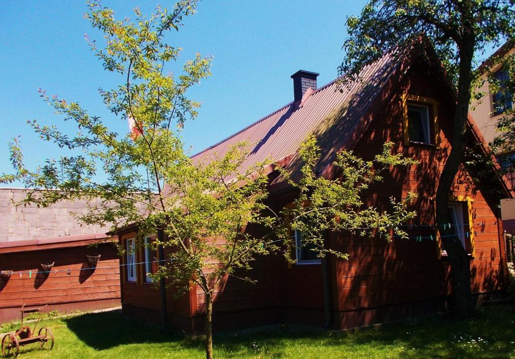 una casa roja con un árbol delante en Bogdanówka en Supraśl