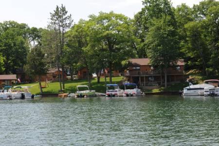 a group of boats parked on the water near a house at Clear Lake Resort in West Branch