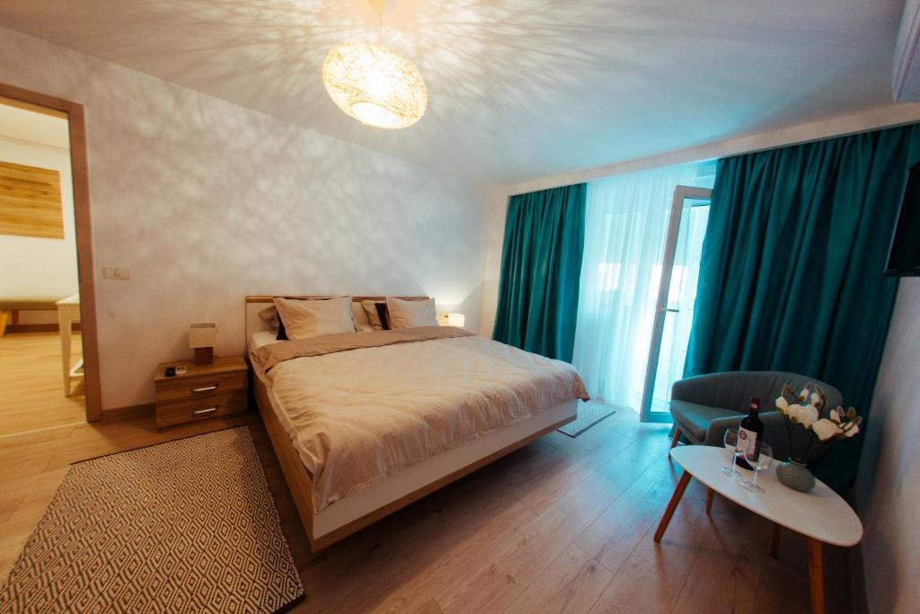 a bedroom with a bed with blue curtains and a chair at Urban Living Apartment in Timişoara