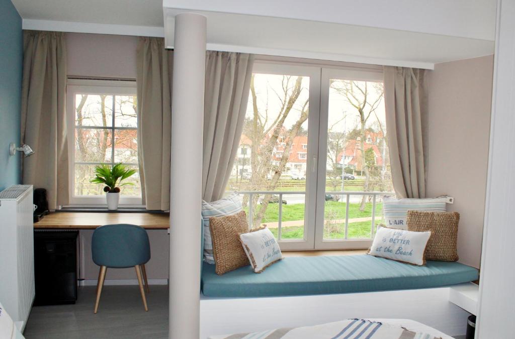 um quarto com uma cama, uma secretária e uma janela em B&B Villa Verde em De Haan