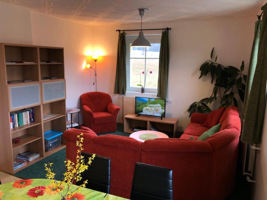 a living room with a red couch and two chairs at Apartments Mirror in Krásná Lípa