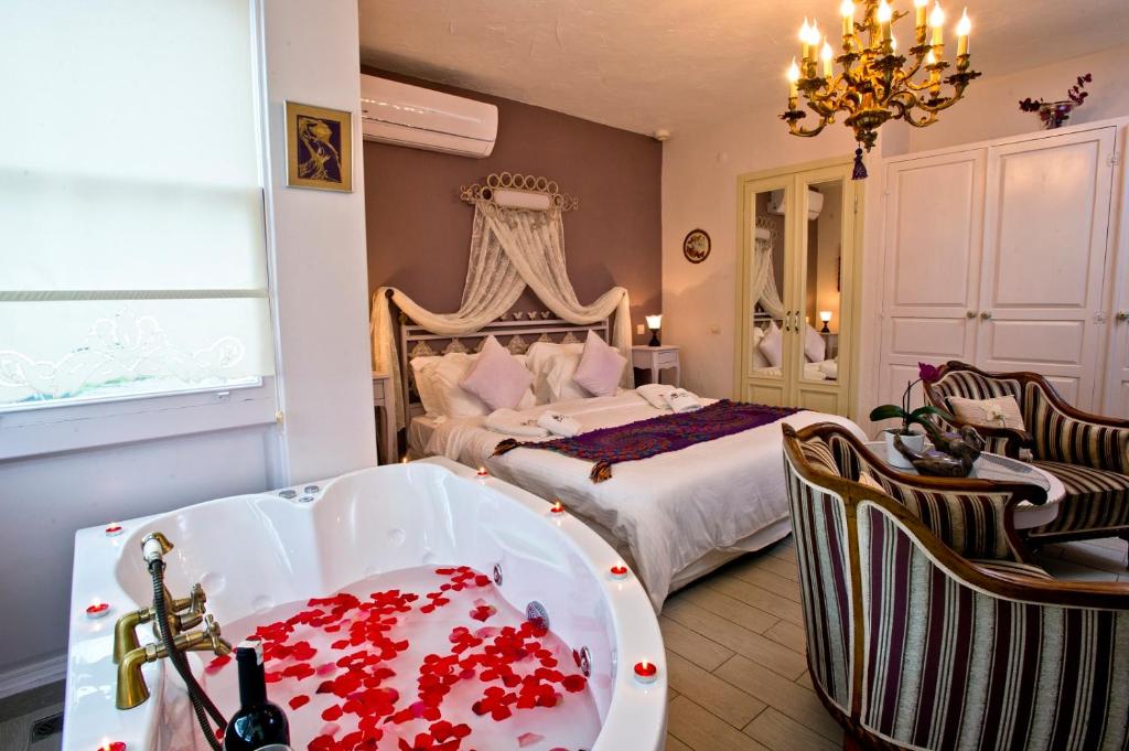 1 dormitorio con 1 cama con bañera llena de rosas rojas en Alaçatı Sultan Konak Butik Otel ℳℛ Luxury Concept, en Alacati