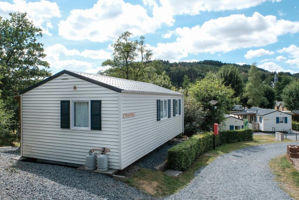 ein kleines weißes winziges Haus auf einer Schotterstraße in der Unterkunft Chalet Arran in Enscherange