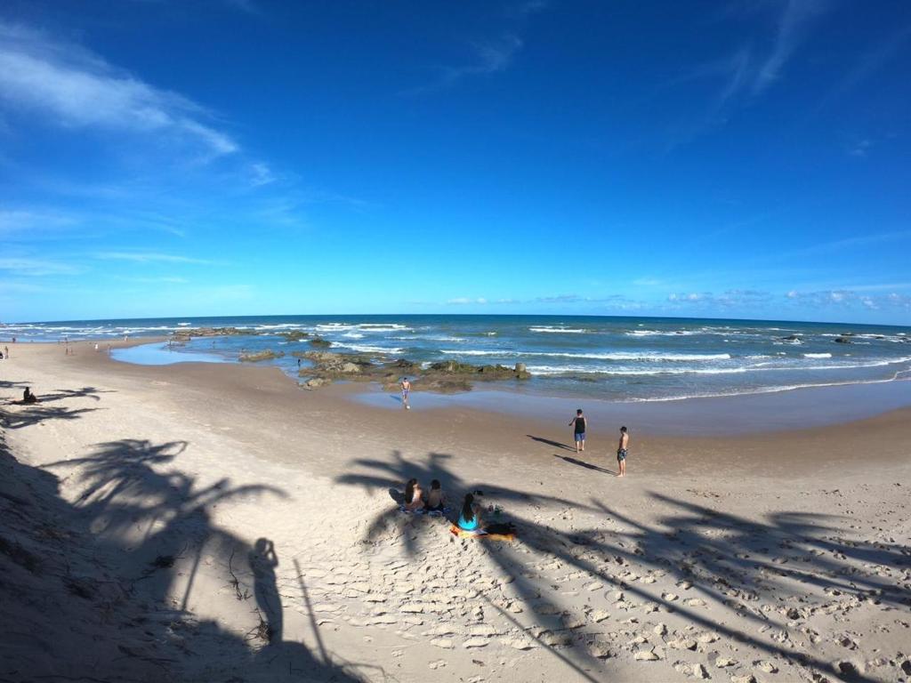 um grupo de pessoas em uma praia com o oceano em Recanto Verde - Praia de Santo Antônio em Diogo