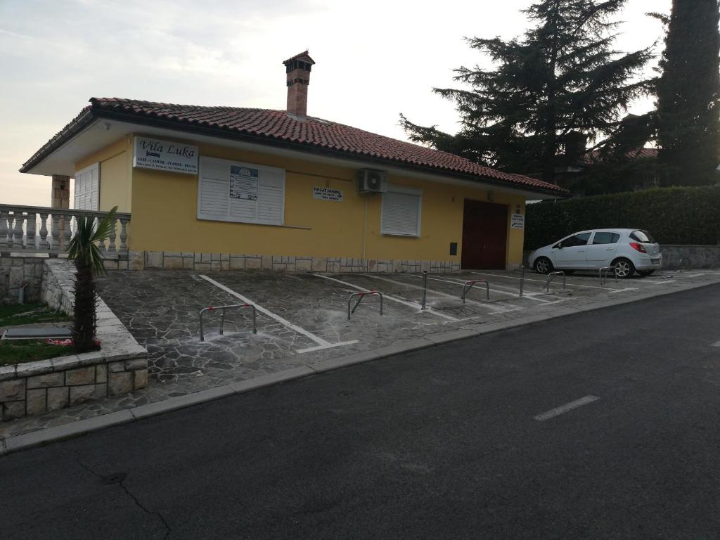 una casa amarilla con un coche aparcado delante de ella en Guest House Vila Luka, en Portorož