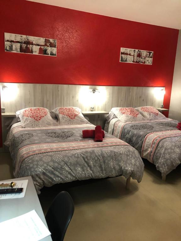 ヴィルヌーヴ・シュル・ロットにあるHotel des Rempartsの赤い壁のベッドルーム1室(ベッド2台付)