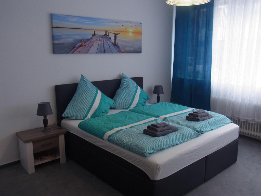 a bedroom with a bed with blue pillows and a painting at City Wohnung Mozart in Saarbrücken