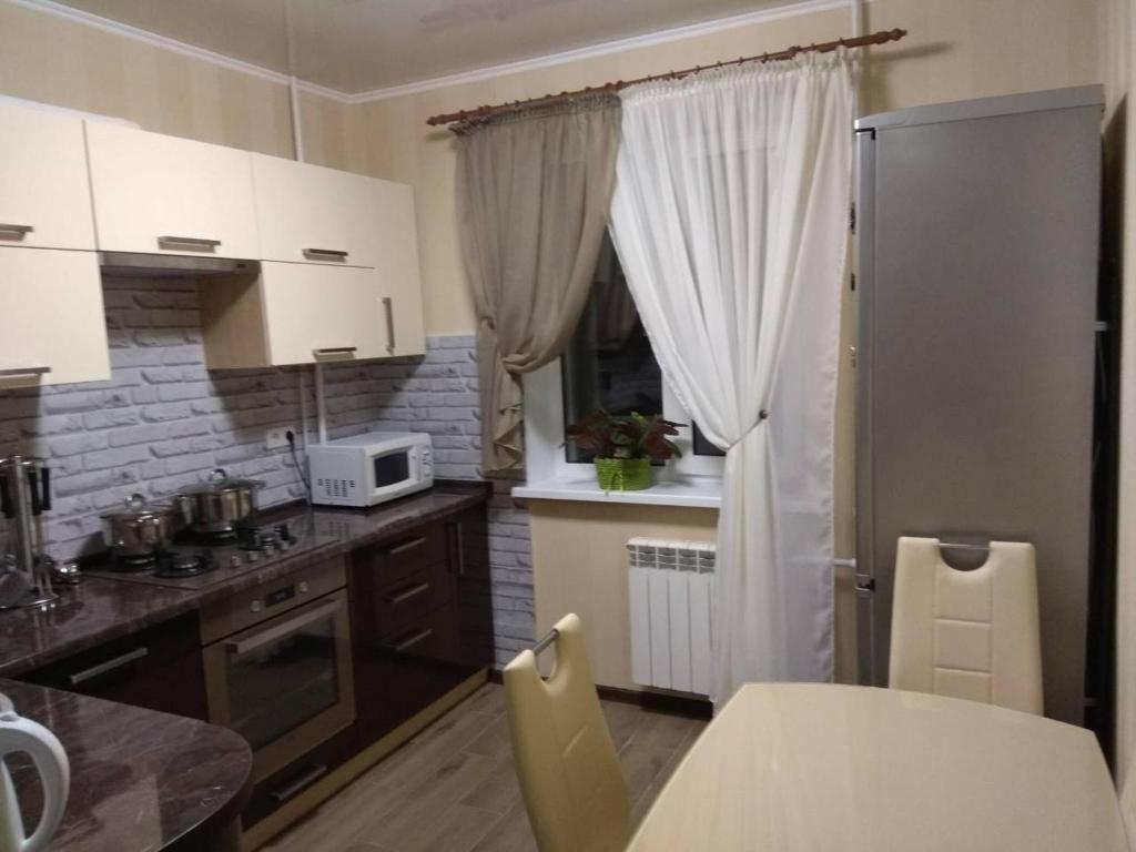 a kitchen with white cabinets and a table with chairs at вулиця Електрометалургів in Nikopol