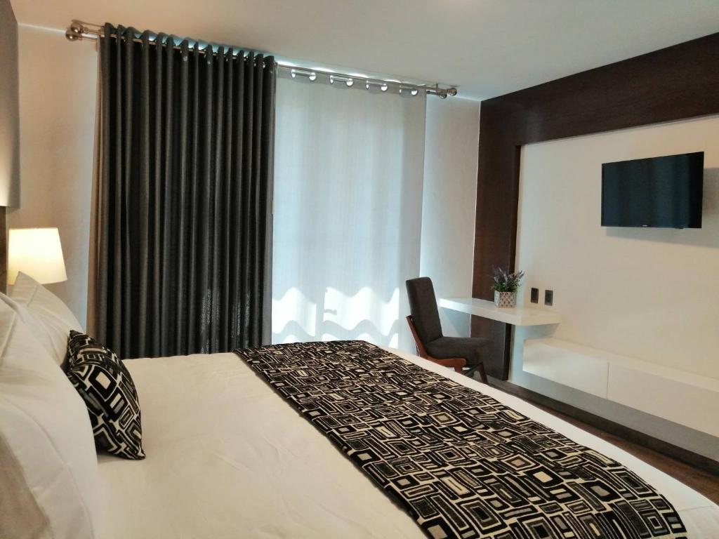 Habitación de hotel con cama, silla y ventana en Hotel Corral Grande en Jamay