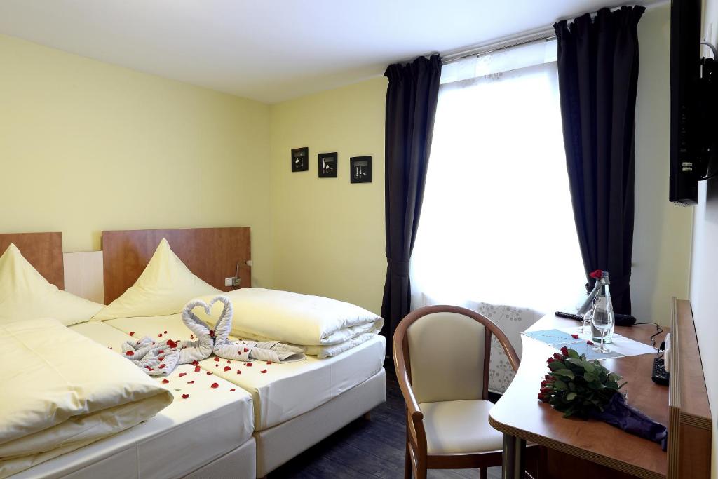 a bedroom with a bed and a desk and a window at Hotel Europa - Restaurant in Rüsselsheim