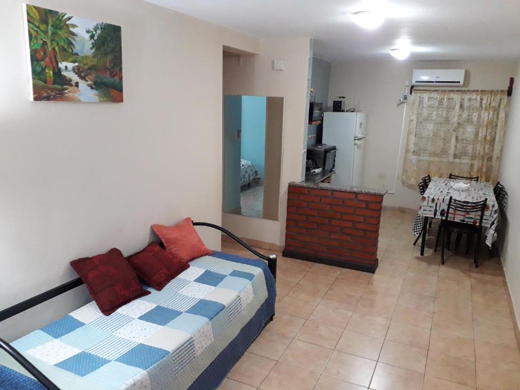 1 dormitorio con 1 cama con almohadas rojas y cocina en Departamento 48 en Puerto Iguazú