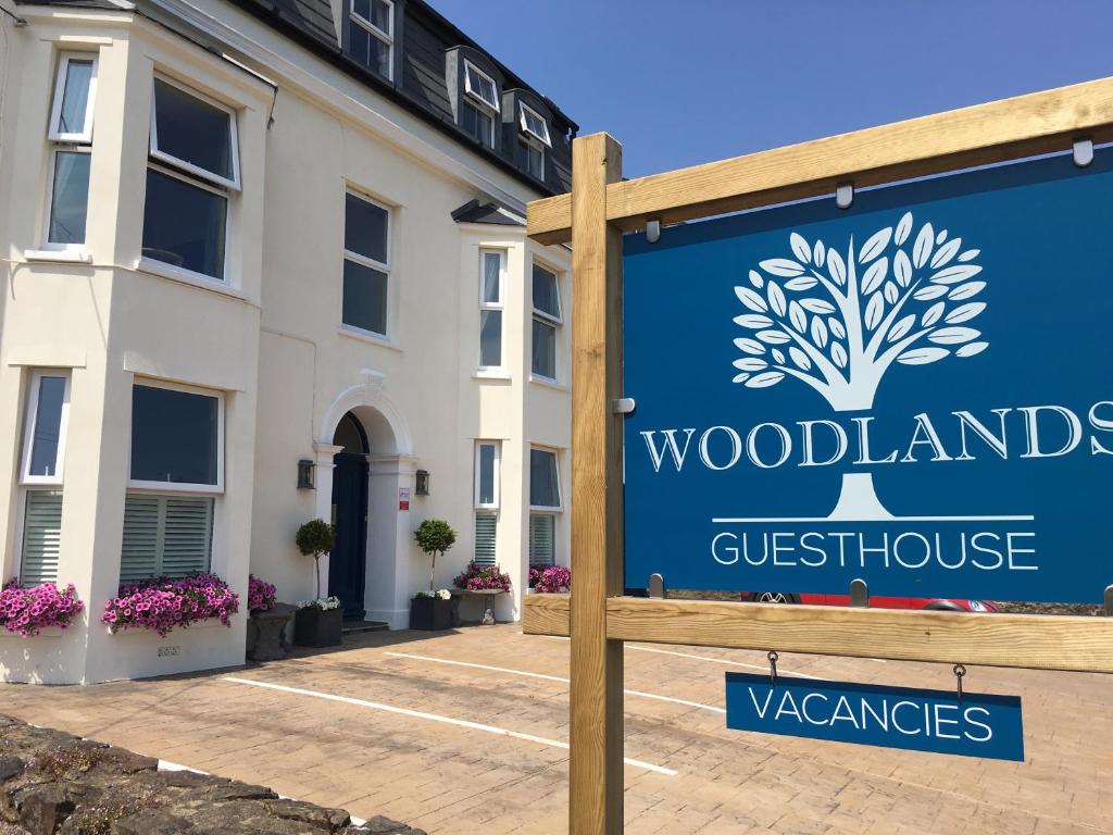 a sign for a guest house in front of a building at Woodlands Guest House in Saundersfoot