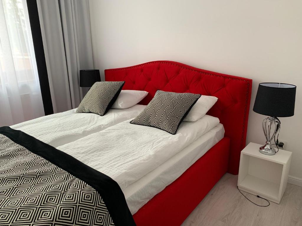 a bed with a red headboard and two pillows at Apartament Zacisze De LUX in Malbork