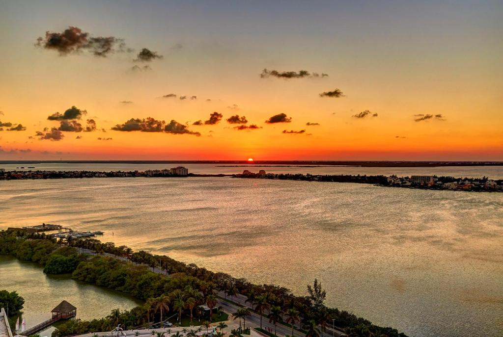 a sunset over a body of water with trees at Royalton CHIC Cancun, An Autograph Collection All-Inclusive Resort - Adults Only in Cancún