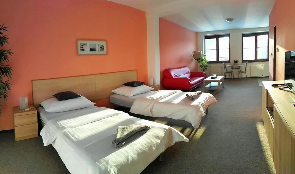 オストラヴァにあるPenzion Exoticのベッド2台と赤い椅子が備わる客室です。