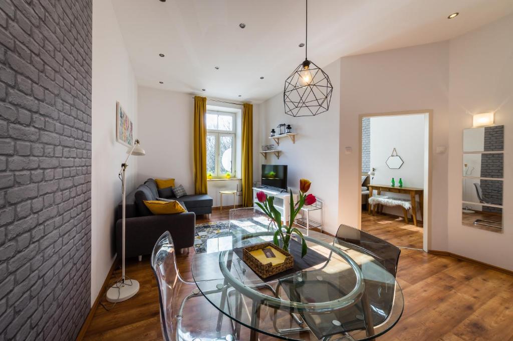 a living room with a glass table and a brick wall at Apartamenty Bosacka WAWELOFTS in Krakow