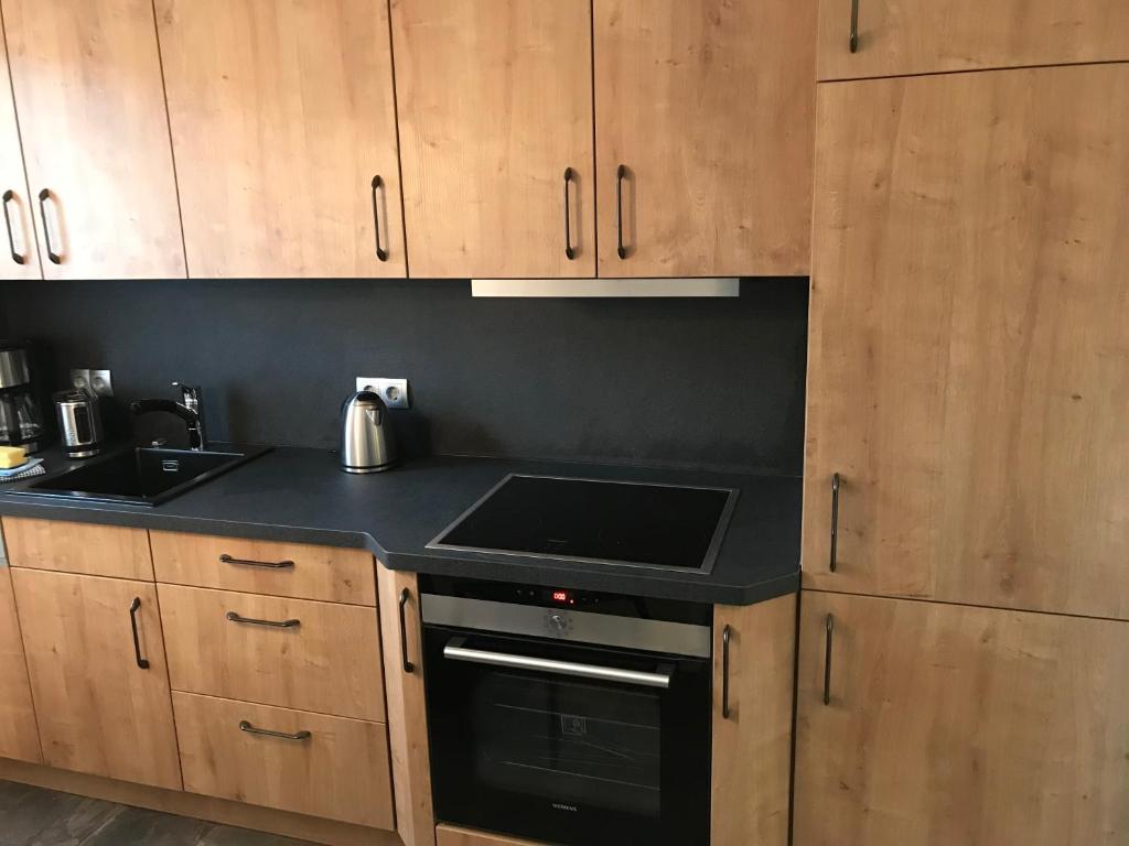 uma cozinha com armários de madeira e um forno de fogão preto em Zentrum Apartment Bad Schandau em Bad Schandau