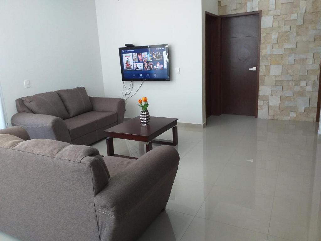 ein Wohnzimmer mit einem Sofa, einem Tisch und einem TV in der Unterkunft RENTA VACACIONAL A 2 CUADRAS DE LA PLAYA O MALECON DE MAZATLAN in Mazatlán