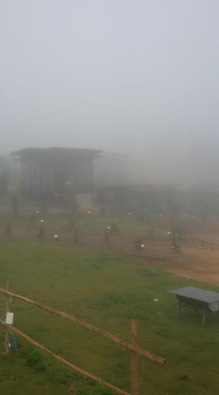 a field with a fence and a bench in the fog at Music Khao Kho in Khao Kho
