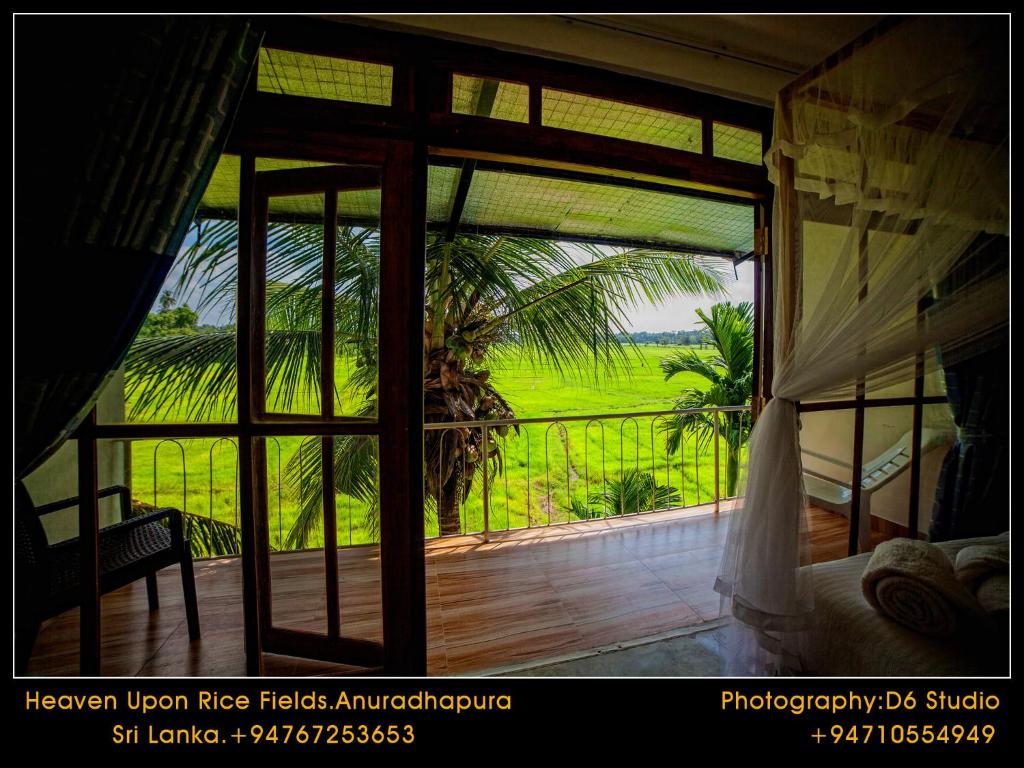 a bedroom with a view of a green field through a window at Heaven Upon Rice Fields in Anuradhapura
