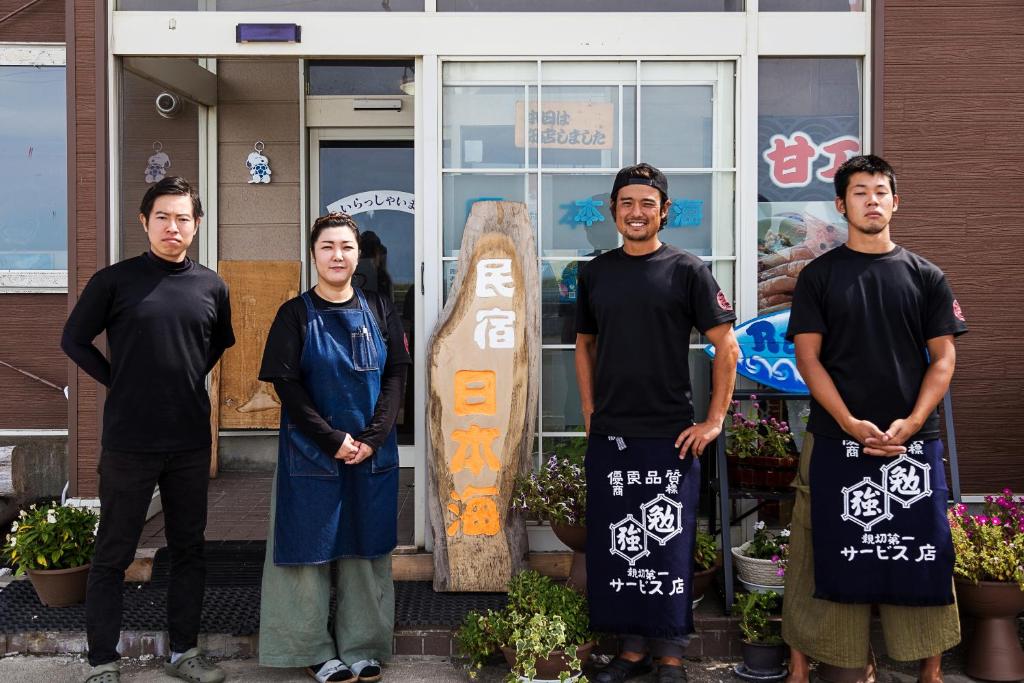 Un groupe d'hommes debout à côté d'un snowboard dans l'établissement Minshuku Nihonkai, à Ishikari