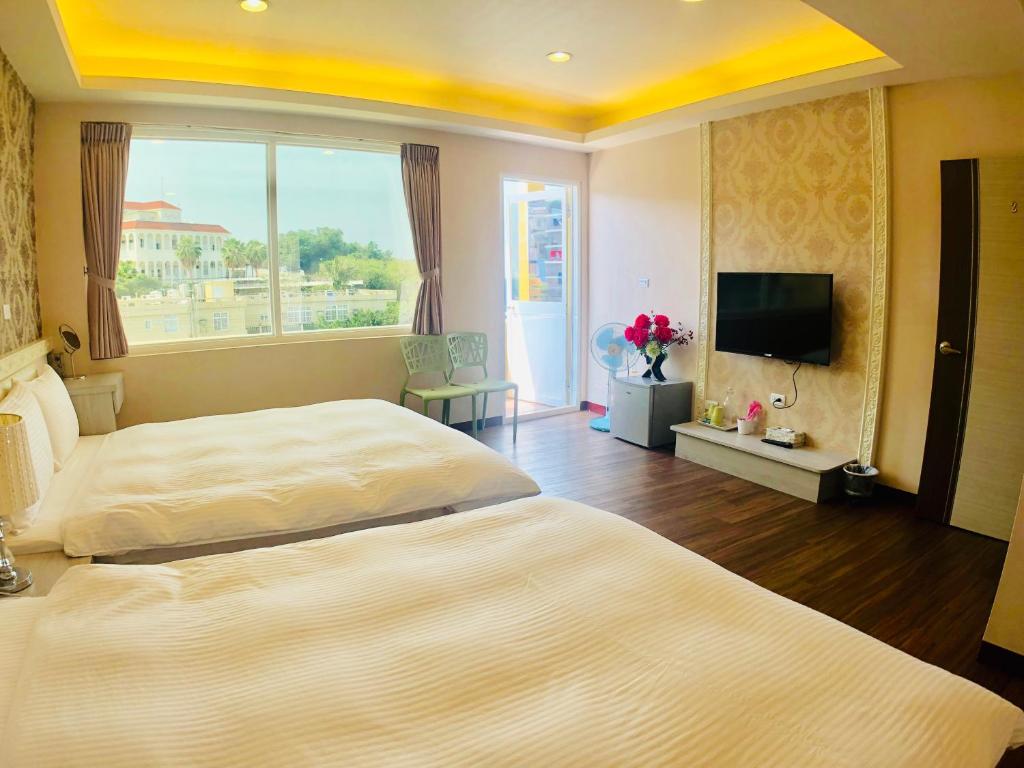 1 Schlafzimmer mit 2 Betten und einem Flachbild-TV in der Unterkunft 夢海民宿 in Xiaoliuqiu