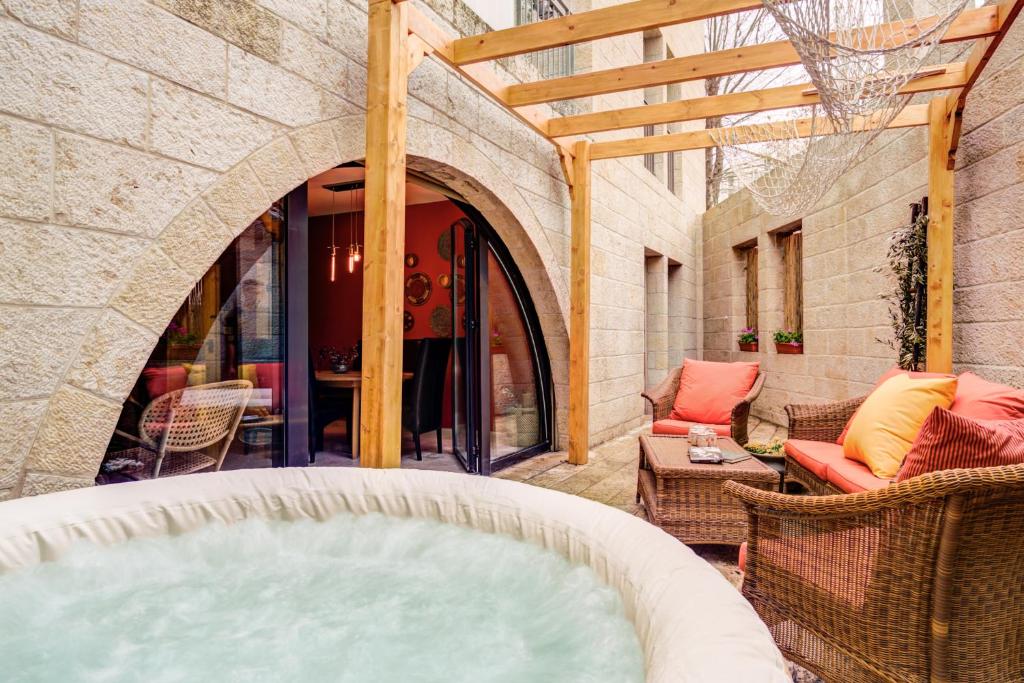 a hot tub on a patio with a table and chairs at Jacuzzi & Secret Garden in David's Village by FeelHome in Jerusalem
