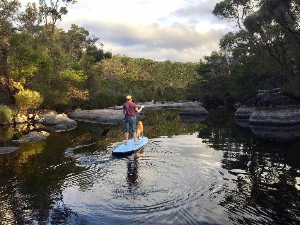 a man and a dog on a paddle board in a river at Che Sara Sara Chalets in Walpole