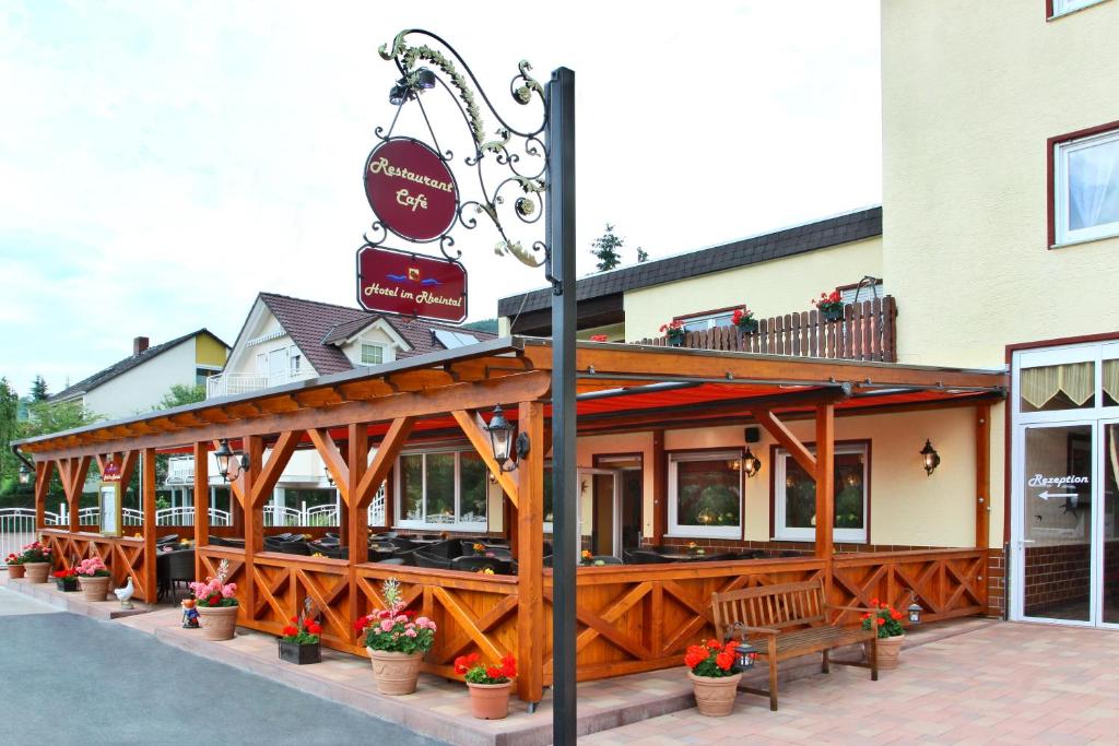 a building with a restaurant with benches in front of it at Hotel im Rheintal in Kamp-Bornhofen