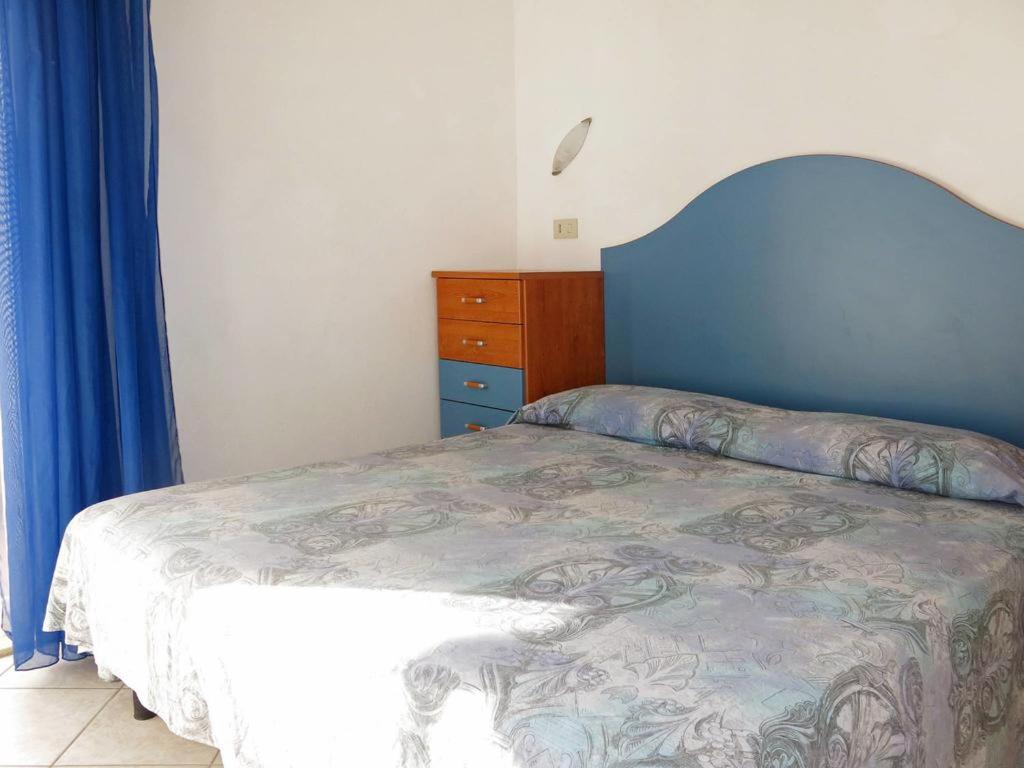 a bedroom with a bed with a blue headboard and a dresser at lorecasa in Porto Garibaldi