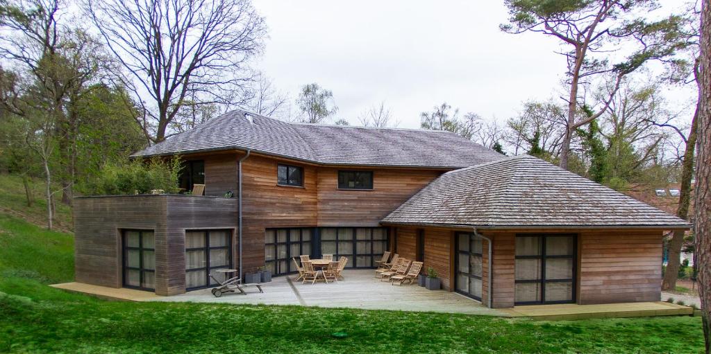 ein großes Holzhaus mit einer Terrasse im Gras in der Unterkunft VILLA KB'HOME in Le Touquet-Paris-Plage