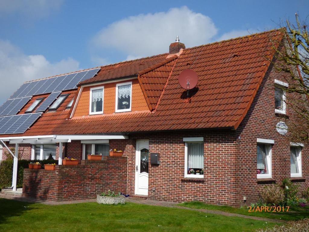 a brick house with solar panels on the roof at Ferienwohnung Hanne in Berumbur