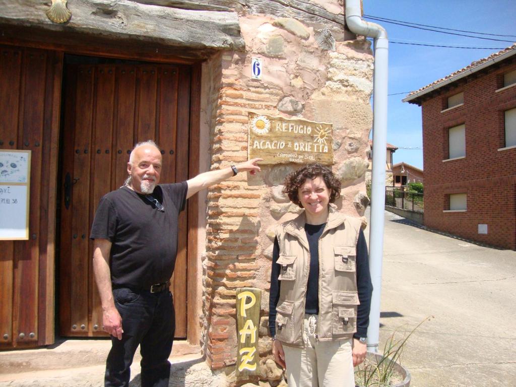 Un uomo e una donna in piedi davanti a un palazzo di Refugio peregrinos Acacio & Orietta a Viloria de Rioja