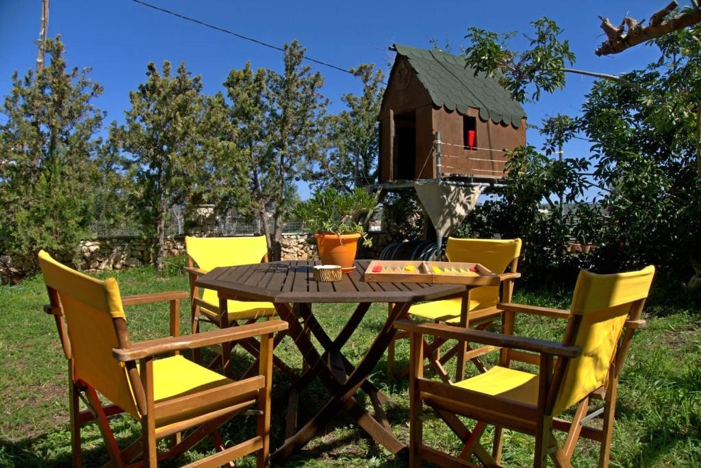 una mesa y sillas con una casa de aves en el fondo en Diamant's Place with Treehouse Garden, en Kounoupidhianá