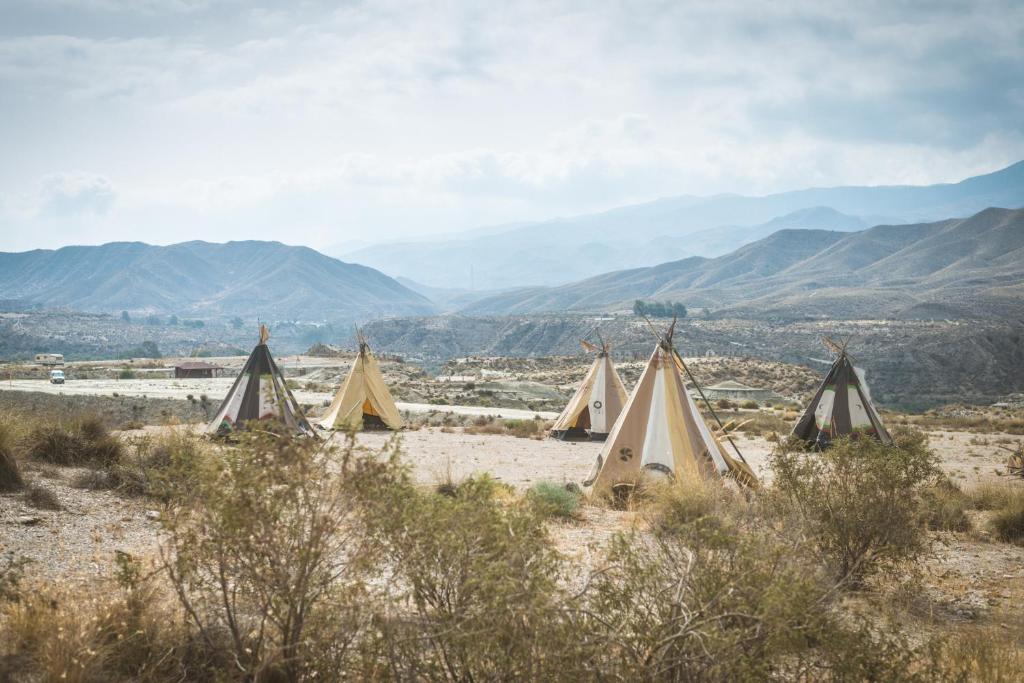 un grupo de tiendas en el desierto con montañas en el fondo en Camping Fort Bravo, en Tabernas