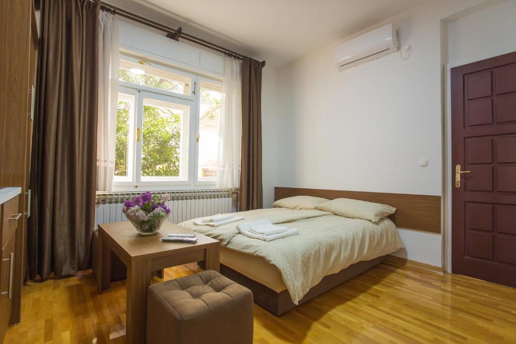 um quarto com uma cama, uma mesa e uma janela em Apart AS em Mostar