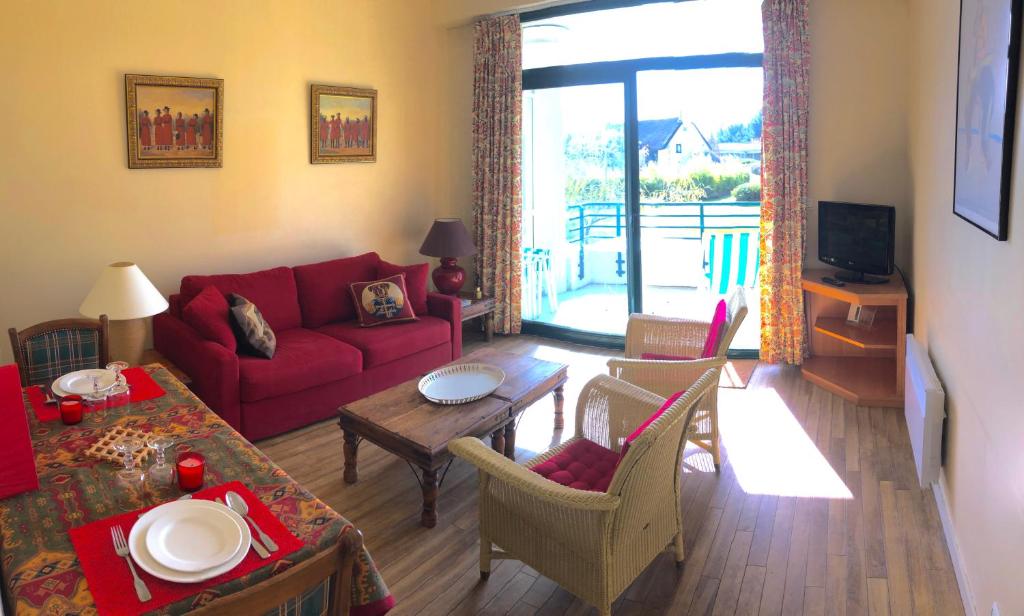 a living room with a red couch and a table at SWING RESIDENCE GOLF LA BAULE in Saint-André-des-Eaux